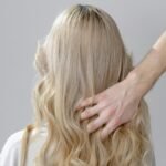 A woman with blonde curls styled gently in a hair salon setting.