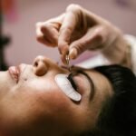 Close-up of a woman receiving eyelash extensions at a beauty salon.